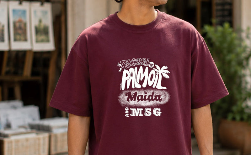 Person wearing a maroon t-shirt with white text standing outdoors.